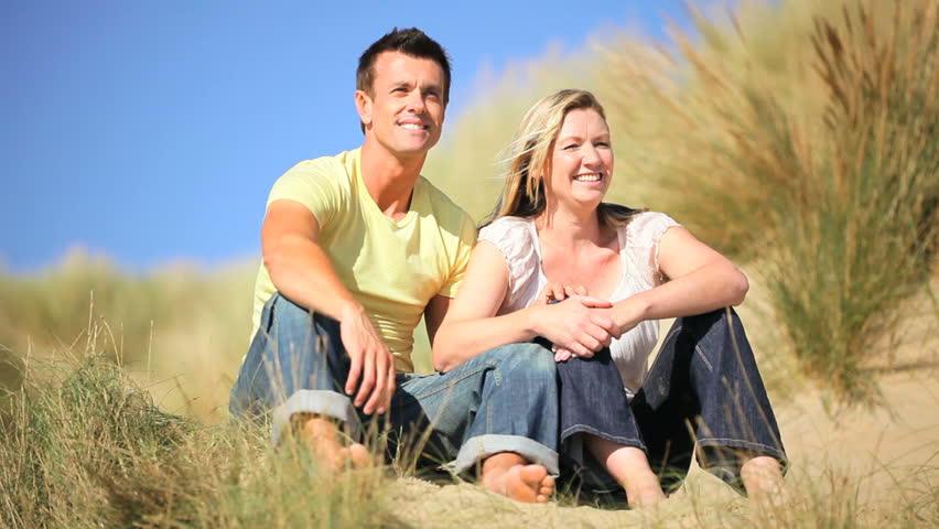 Attractive young caucasian family enjoying time together & the children having fun playing in sand dunes