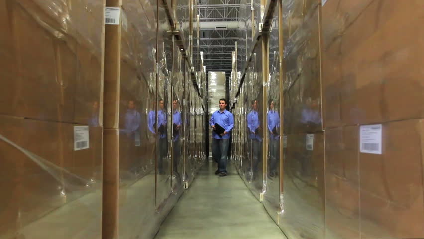A warehouse foreman checks inventory amidst stacks of boxes 