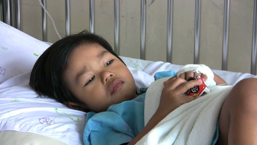 A sick little boy takes comfort in his toy cars while recovering from being ill in the hospital.