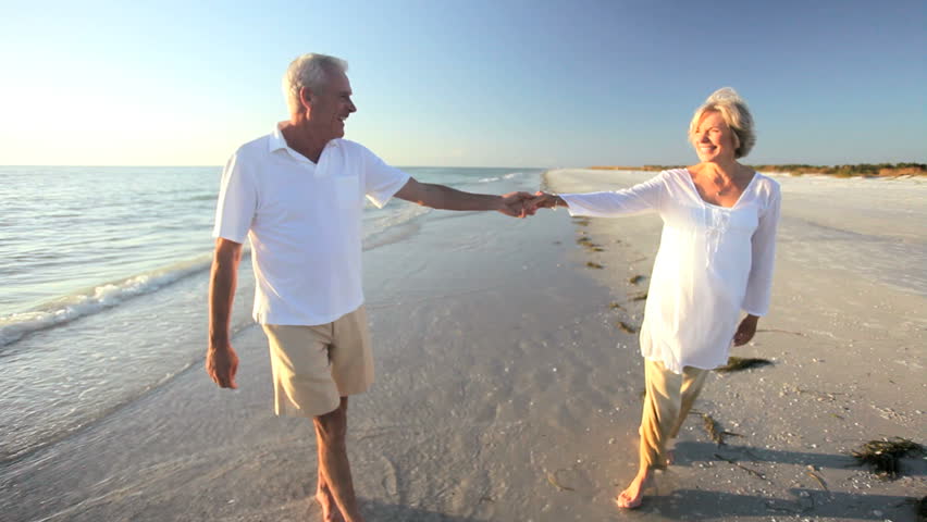 Carefree senior couple romantically dancing together on a beach at sunset