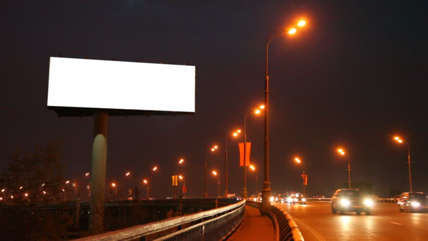 empty billboard near bridge with moving cars in night city