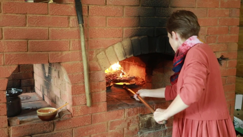 Hd00 06a Girl In National Dress Is Cooking In A Fireplace Pancakes In A