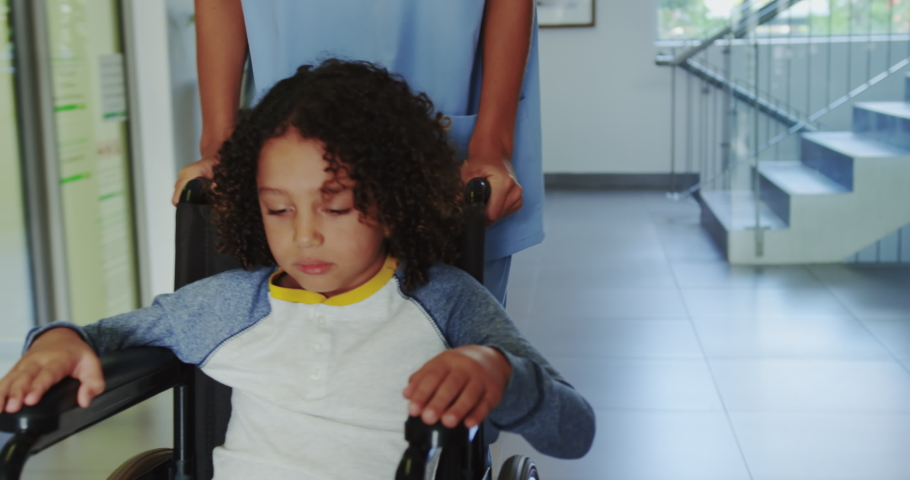 4k00 08front View Of Doctor Pushing African American Boy In