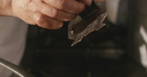 Super slow motion macro of a hand of middle aged chef grating black truffle in pan (close up)