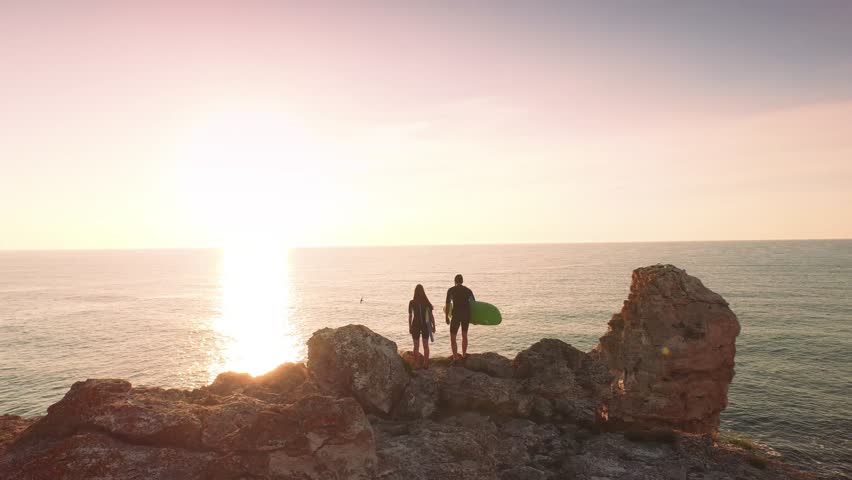 Aerial Fly By Surfers Couple Standing On Edge Of A Cliff Ocean Sunset Horizon Sky Summer Aerial Fly By Surfers Couple Standing On Edge Of A Cliff Ocean Sunset Horizon Sky Summer