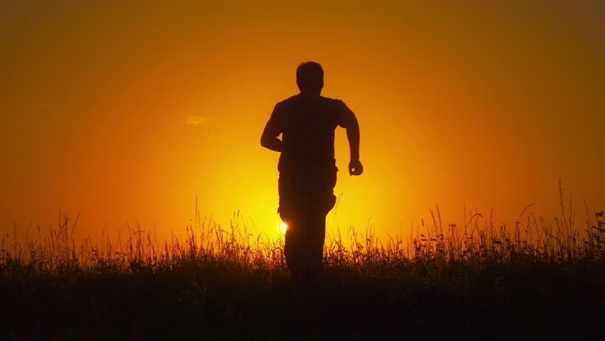 Man Running In The Fields Towards Setting Sun, Spreading His Hands ...