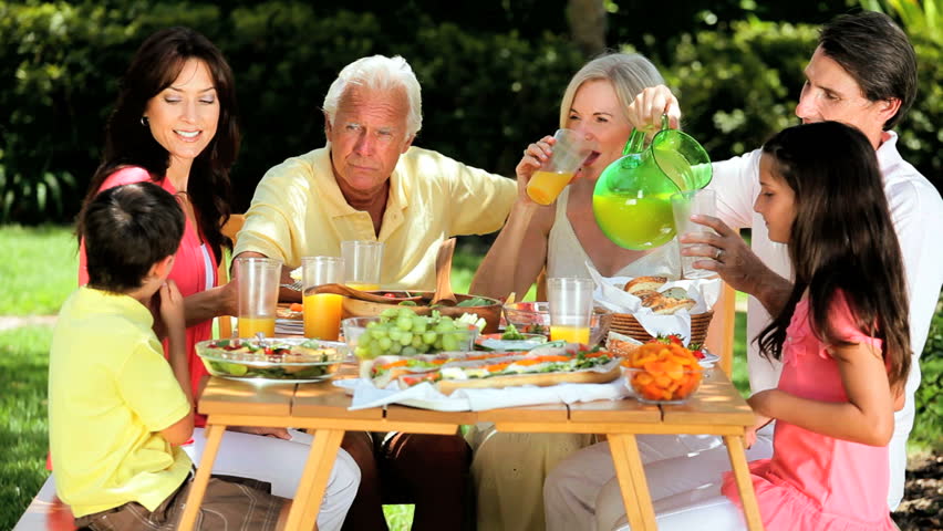 Extended Family Group Sitting Down To Meal As Grandmother Serves Food ...