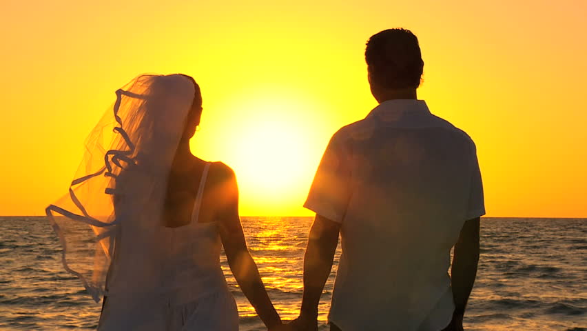 Happy Couple Holding Hands And Walking Away From Camera Into The Sunset ...