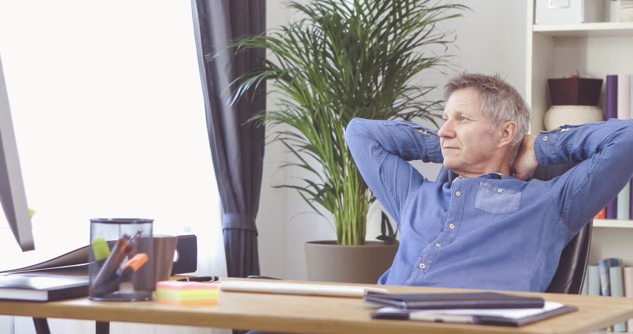Portrait Of A Man With Grey Hair Relaxing At His Desk In Home Portrait Of A Man With Grey Hair Relaxing At His Desk In Home Office