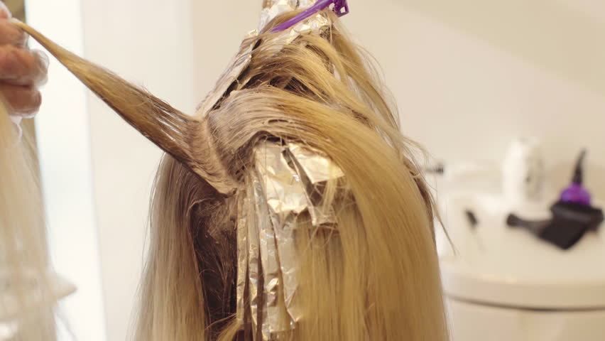 Brush Paint Over The Hair Roots From Blonde Close Up Hairdresser Dye The Hair Blonde Girl Sitting In A Beauty Salon Barber Brush