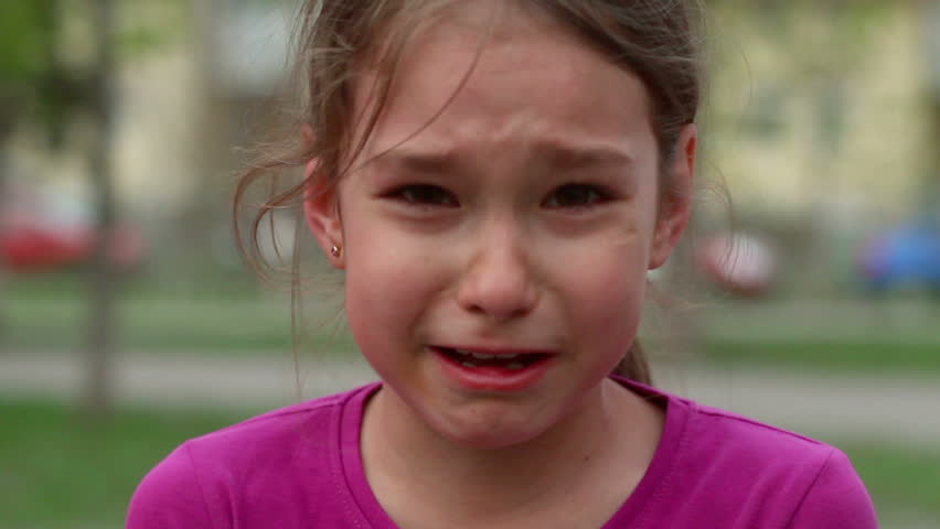 little-girl-sits-in-the-grass-and-makes-a-funny-face-at-the-camera