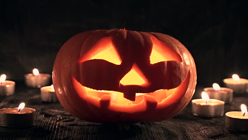 carved halloween pumpkin lights inside with flame on a black background with lighted candles close up - Halloween Background Video carved halloween pumpkin lights inside with flame on a black background with lighted candles close up - Halloween Background Video