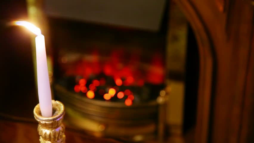 Burning Candle Stands In Magnificent Candlestick In Front Of Fireplace