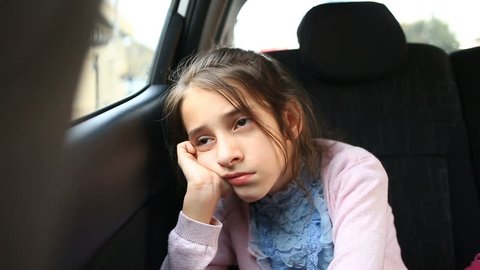 Little girl, bored in the car - looking out the window through the window - street reflection