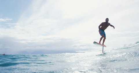 Surfer on hydrofoil surfboard riding blue ocean wave. Futuristic surfing on foil hover board.