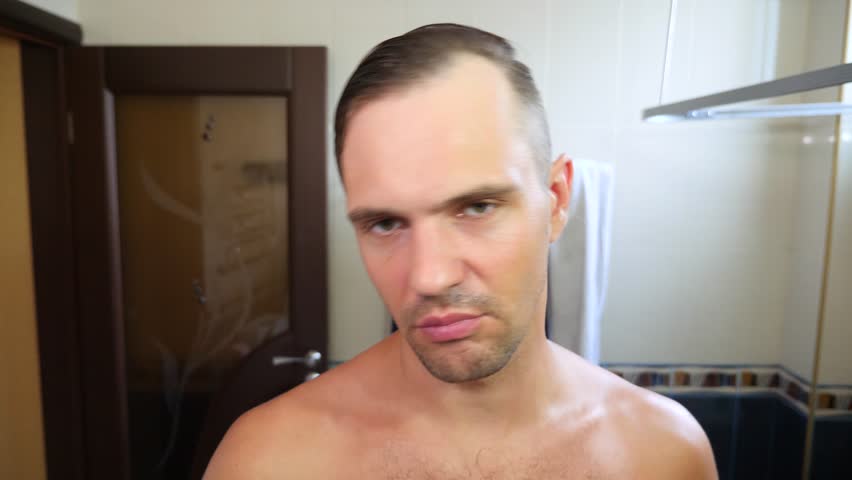 Young Attractive Man Inspects A Receding Hairline In The Bathroom