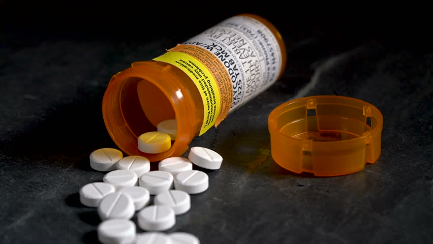 Macro video of Oxycodone Opioid tablets on slate table with focus moving away from the camera