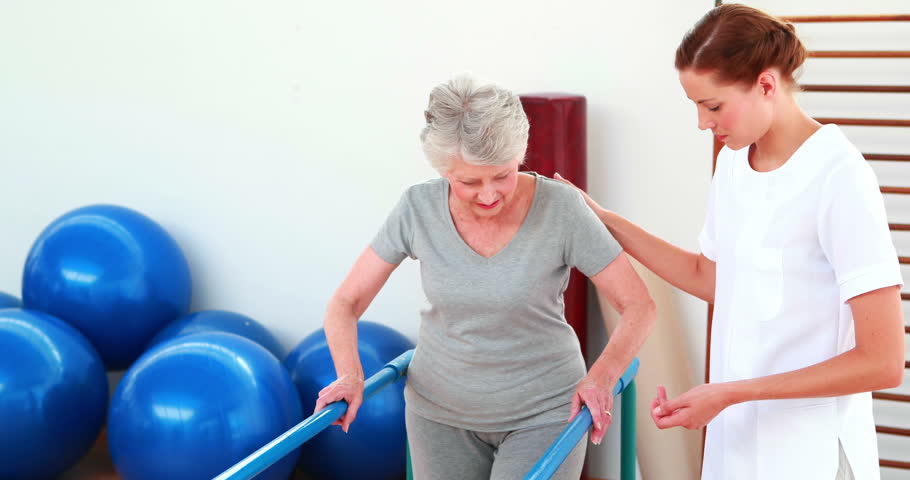 Physical Therapist Helping Patient Walk With Parallel Bars At The ...