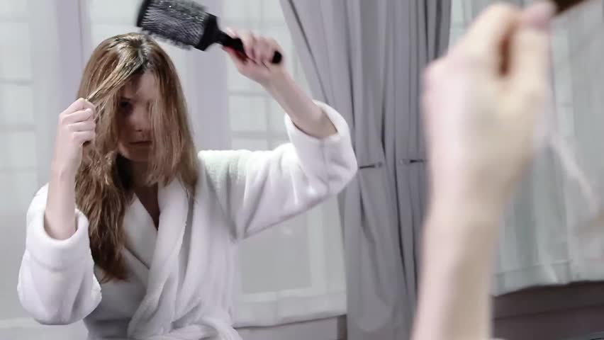 Hd00 25a Young Woman In A Robe Looks Into A Mirror As She Brushes