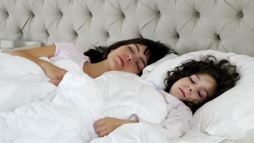 Mother Kissing Her Little Daughter While She Is Sleeping In Bed Stock